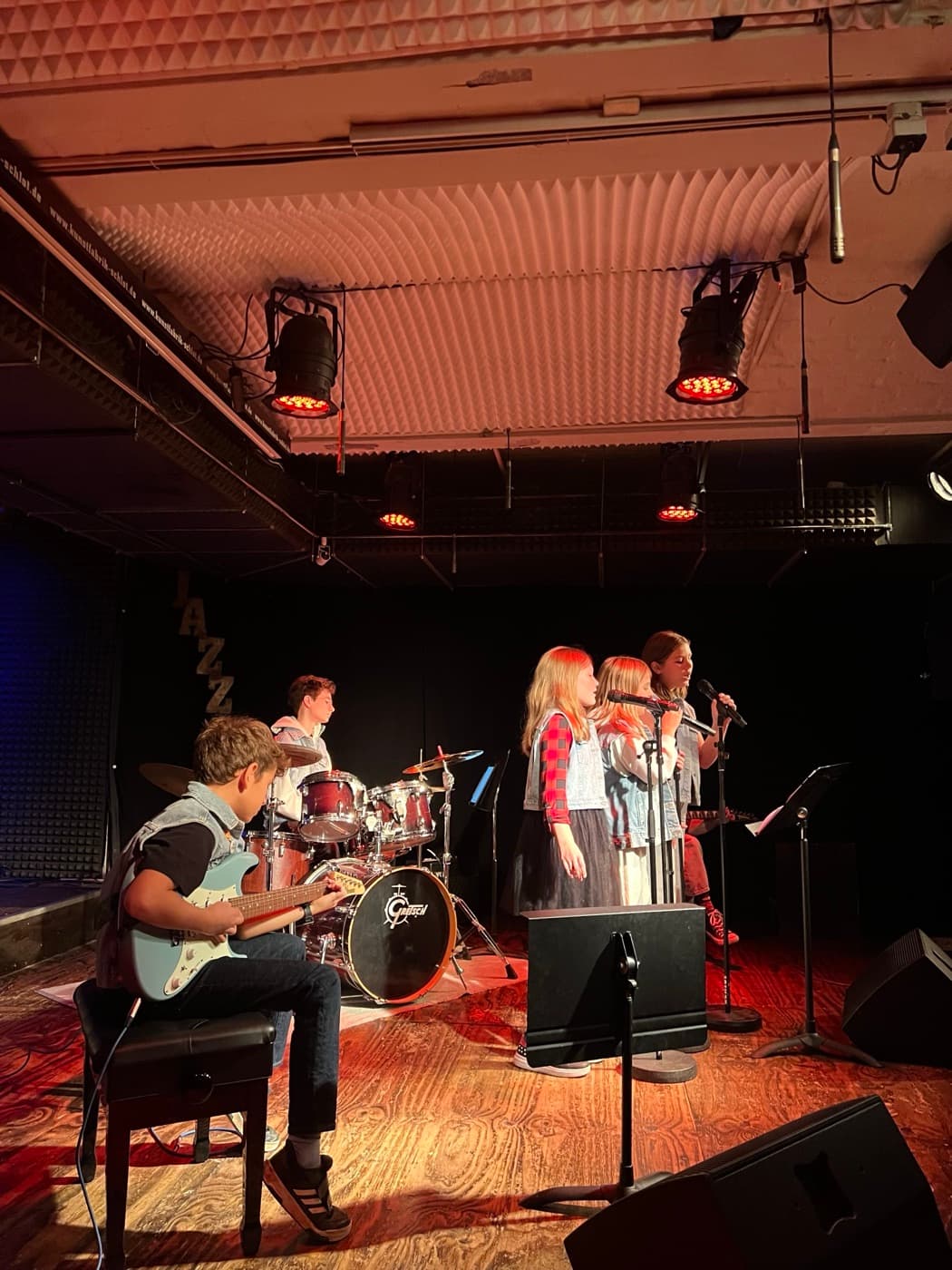 Kid performing with their band on stage at a Rock Academy live show